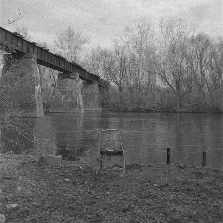 Chair by the abandoned railroad bridge, black and white